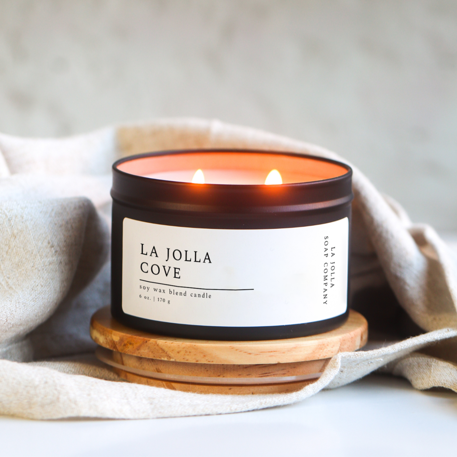 La Jolla Cove Candle in a black tin, inspired by the scenic La Jolla Cove, with fresh scent notes evoking ocean breezes, sunlit coastal cliffs and the tranquility of seaside air.