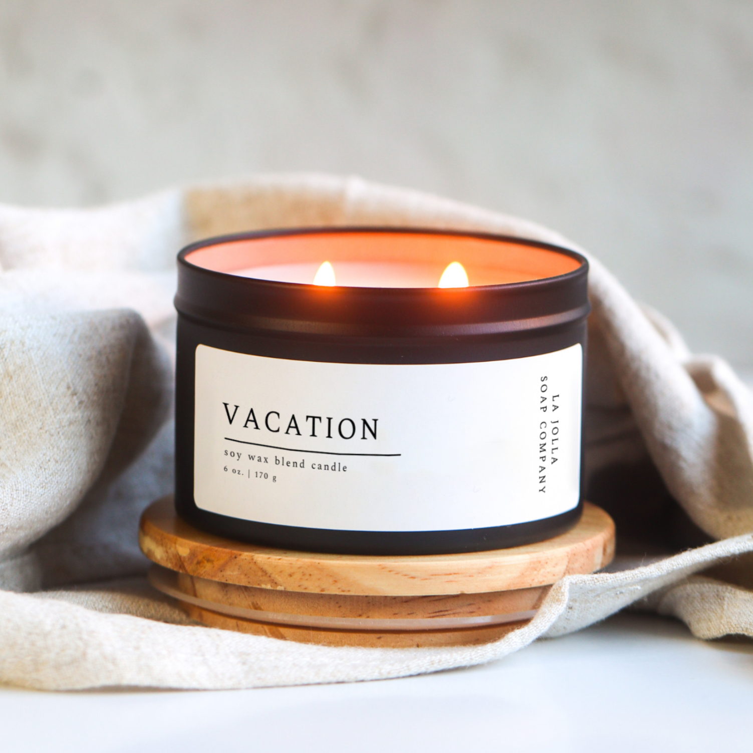 Vacation Candle in a black 6 oz tin. This sensory experience is a soothing blend of oceanic aromas, highlighted by the warmth of cocoa butter, the sweetness of vanilla and the tropical essence of coconut. It evokes memories of a relaxing beach vacation, complete with the gentle caress of sea breezes and the indulgence of tropical delights.
