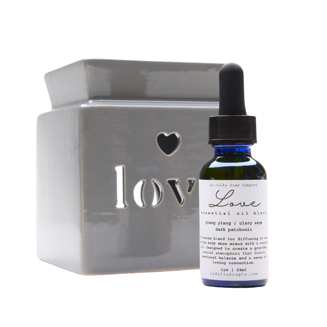 one light grey ceramic oil burner features a cutout heart and 'love' text in a cute, contemporary design.

One LOVE Custom Essential Oil Blend presented in a blue boston round bottle with a dropper lid.