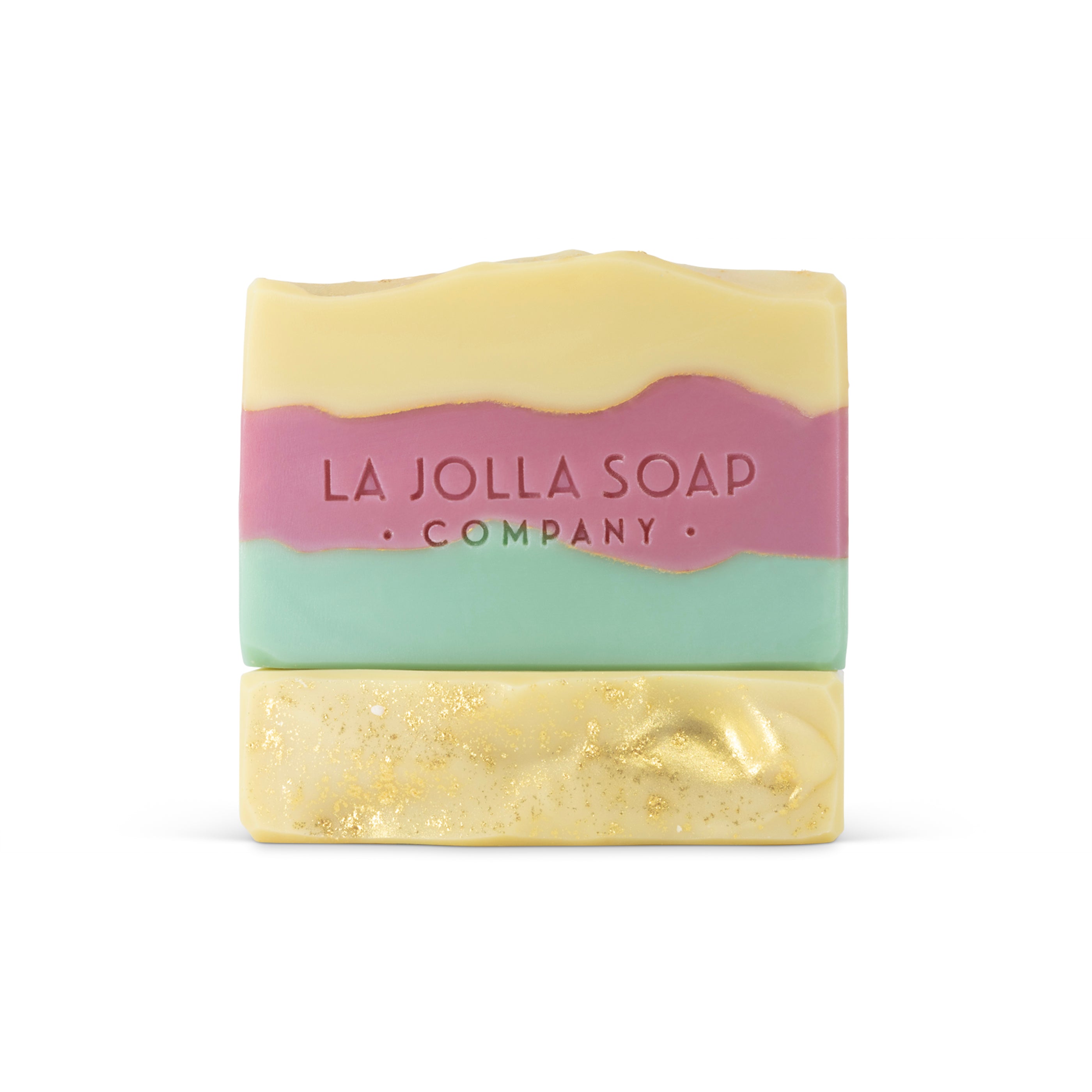 La Jolla Soap Company Two bars of Brand soap with bright layered colors of green, pink and yellow, one stacked on top of the other showing the top side of the soap dusted with gold and the front side of the soaps layered colors view.