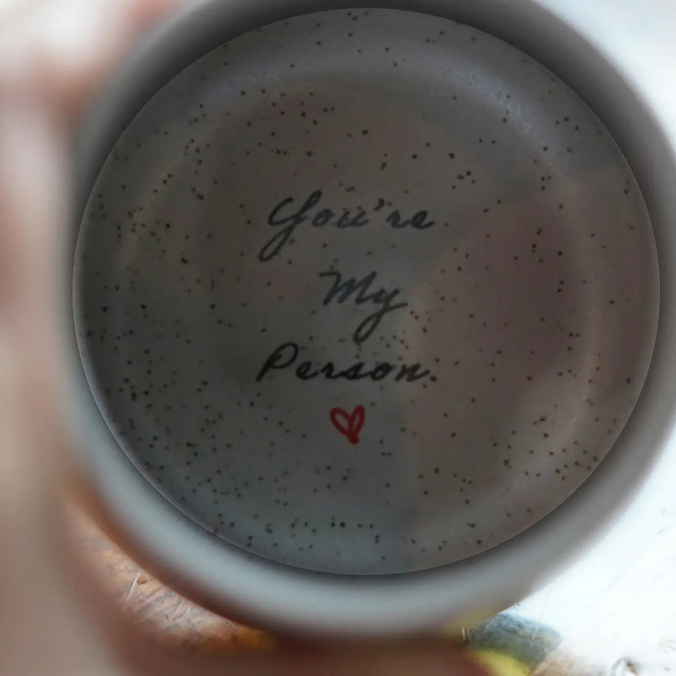 The inside bottom of a handcrafted mug, which reads "You're my Person".